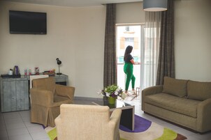 Un salón con sofá, sillón y televisión montada en la pared.
