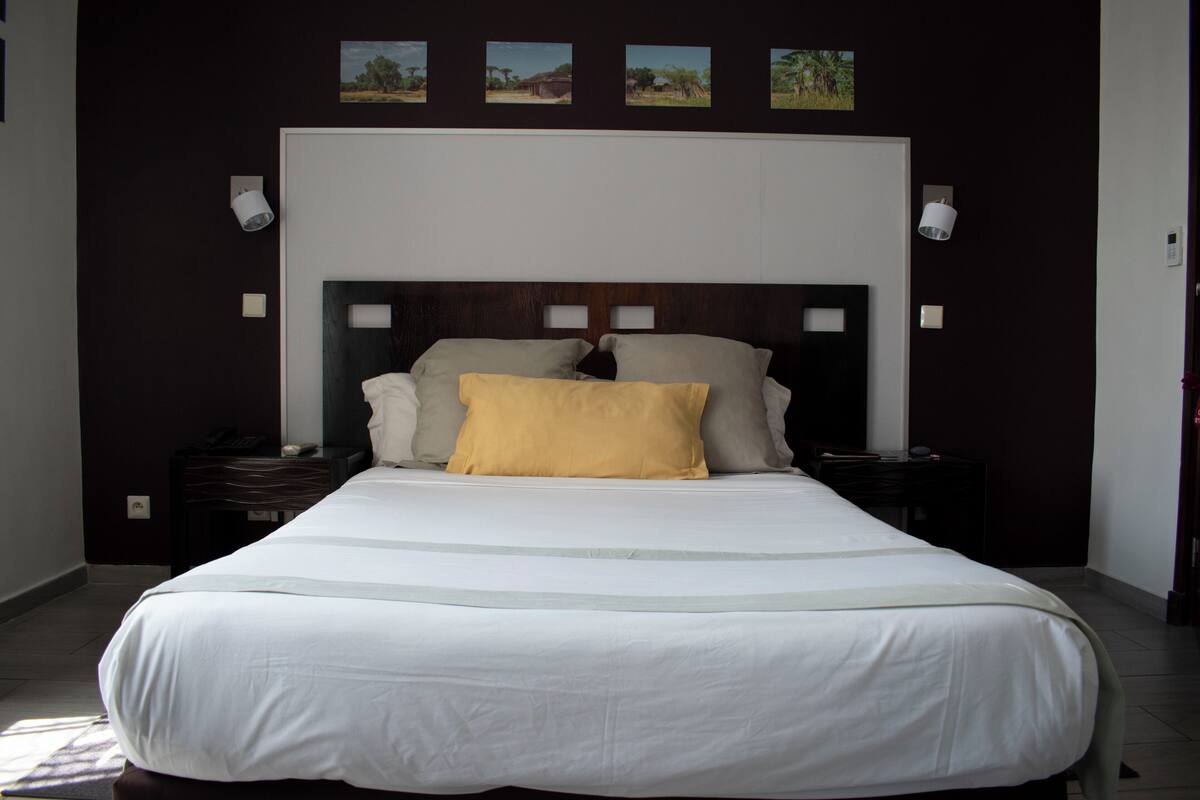 A bed with a white and yellow bedspread, a wooden headboard, and bedside tables with lamps.