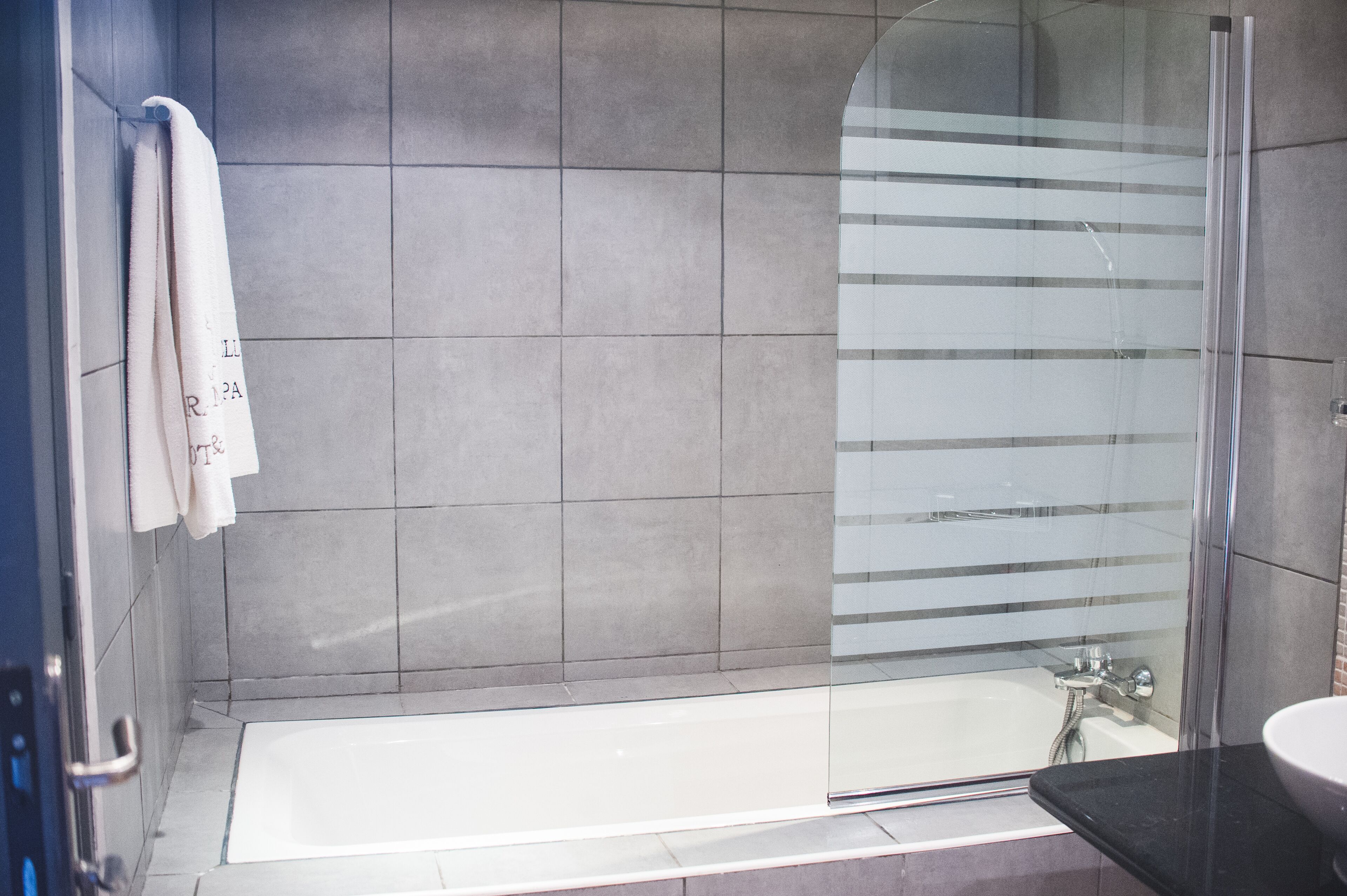 A modern bathroom with a glass-enclosed shower, a bathtub, and a sink.