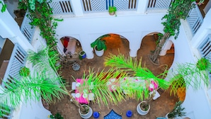 A courtyard with potted plants, a blue fan, and a decorative fountain. - Riad El Kenz (Marrakech)