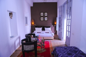 Un dormitorio con cama, una silla, una mesita y alfombra roja.