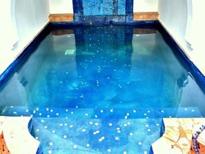 A swimming pool with a clear blue water surface and a few floating objects. - Riad El Kenz (Marrakech)