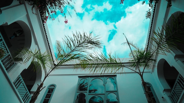 A building with arched windows and a view of the sky through the foliage. - Riad El Kenz (Marrakech)