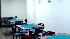 Ein Klassenzimmer mit Tischen und Stühlen, weißen Wänden und einer Tür.