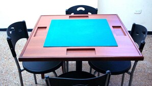 Ein quadratischer Holztisch mit einer blauen Tischmatte, umgeben von vier schwarzen Stühlen.