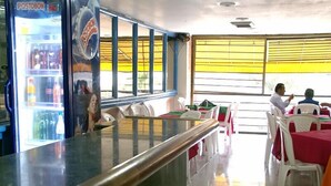 Ein Restaurant mit Tresen, Tischen, Stühlen und einem Kühlschrank.