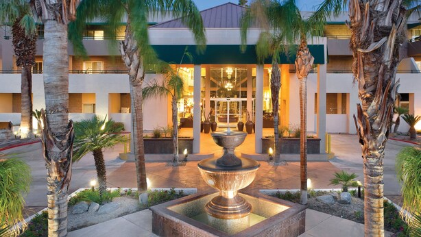 A hotel entrance with a central fountain, palm trees, and a well-lit building facade. - WorldMark Palm Springs (Palm Springs)