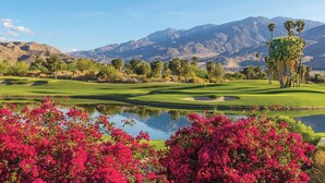 A golf course with a pond in the foreground, palm trees, and mountains in the background. - WorldMark Palm Springs (Palm Springs)