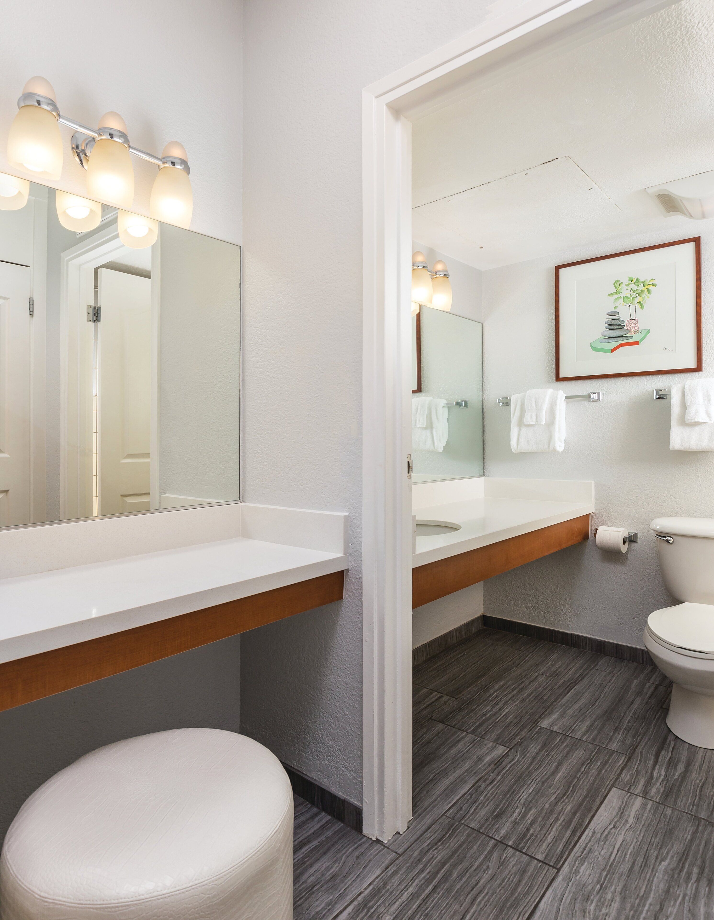 Un baño moderno con tocador blanco, un espejo grande y un inodoro.