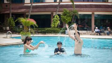 Relax by the pool surrounded by palm trees and a nearby building.