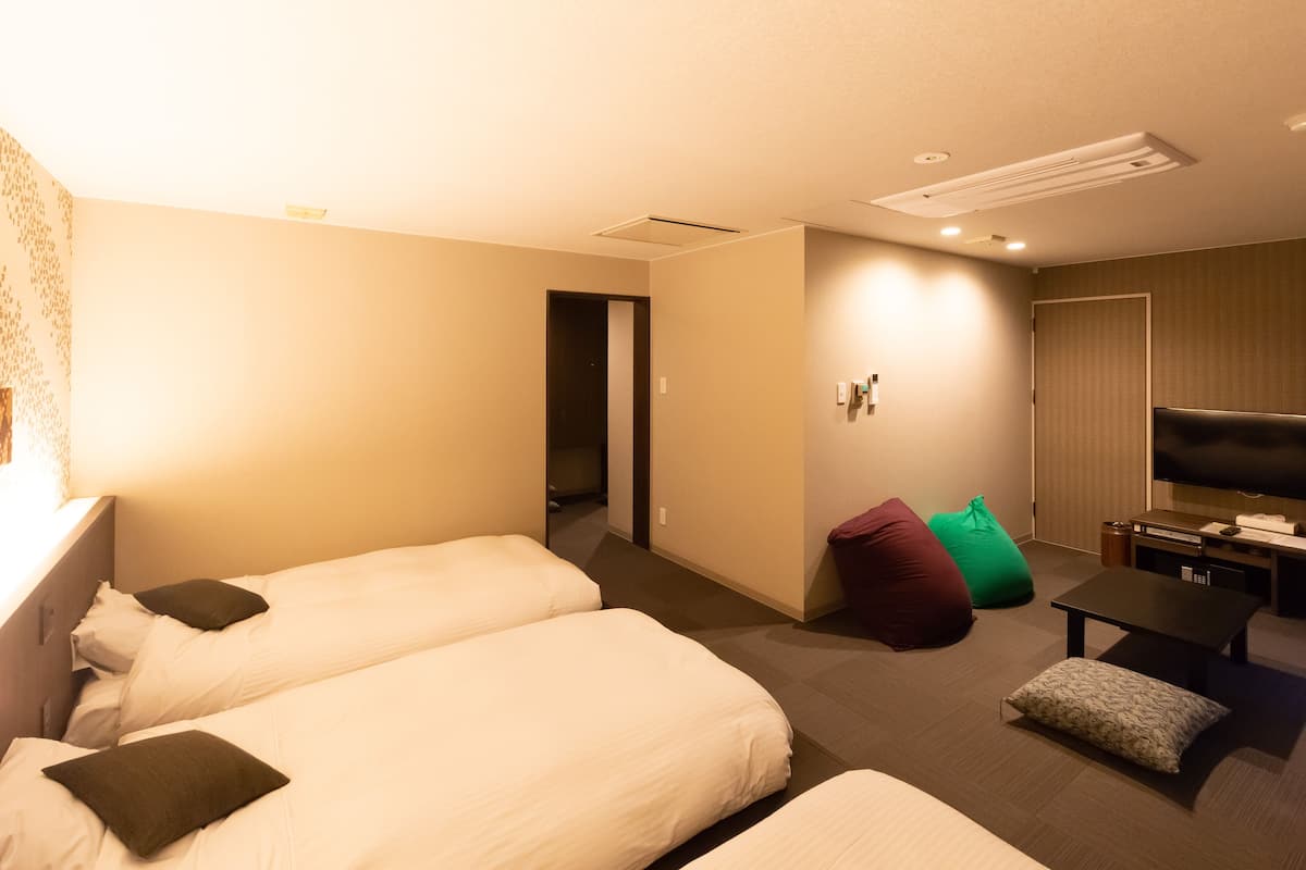 Una habitación de hotel con dos camas, televisión, escritorio y sofá.