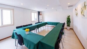 A conference room with a long table, chairs, and a potted plant.