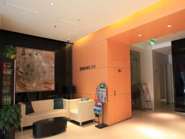 A modern hotel lobby with a reception desk, seating area, and a large abstract painting. - Jinjiang Inn Xian Dayan Tower (Xi'an)
