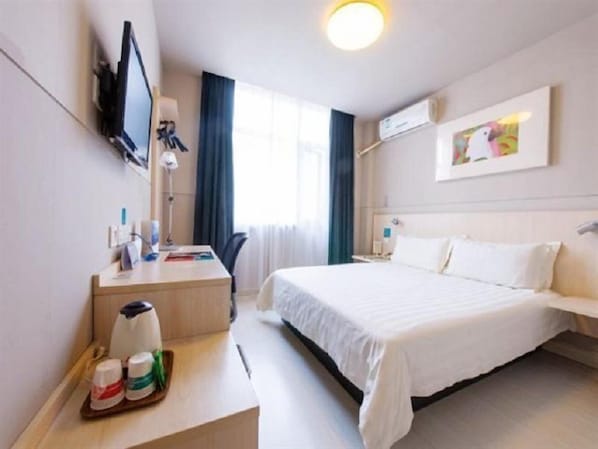 A hotel room with a bed, a desk with a chair, a TV mounted on the wall, and a window with curtains. - Jinjiang Inn Xian Dayan Tower (Xi'an)