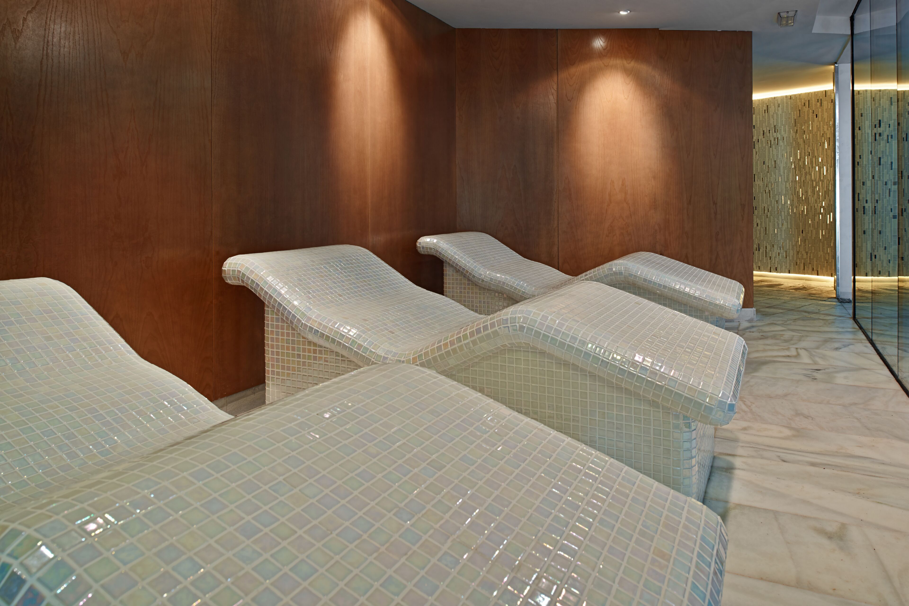 Un espace spa comprenant quatre tables de massage, des murs en bois et un sol carrelé.