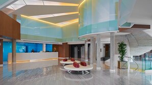 Un lobby moderno con mostrador de recepción, zona de estar y una escalera.
