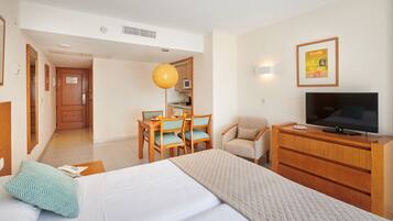 Ein Hotelzimmer mit einem Bett, einem Schreibtisch mit Stühlen, einem Fernseher und einer Küchenzeile.