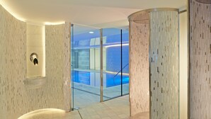 Un interior moderno con una pared curva, una puerta de cristal que da a una zona de piscina y un suelo de mármol.