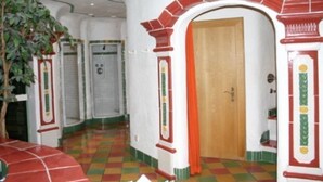 A hallway with a checkered floor, a door labeled "WHIRLBAID", and a plant on the left. - Lukasmayr Hotel (Bruck an der Grossglocknerstrasse)