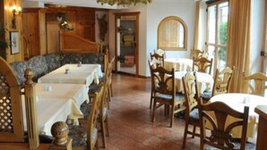 A restaurant with wooden furniture, white tablecloths, and a chandelier. - Lukasmayr Hotel (Bruck an der Grossglocknerstrasse)