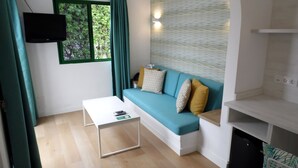 A modern living room with a teal sofa, white coffee table, and a flat-screen TV mounted on the wall. - Canary Garden Club (San Bartolomé de Tirajana)