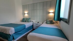 A twin room with two beds, each with teal bedding, a nightstand, and a wall-mounted TV. - Canary Garden Club (San Bartolomé de Tirajana)