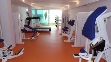A gym with various exercise equipment, including treadmills and weight machines, arranged in a spacious room with orange flooring.