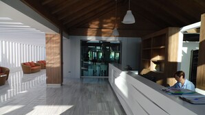 A modern interior with a reception desk, seating area, and a view into the lobby. - Canary Garden Club (San Bartolomé de Tirajana)