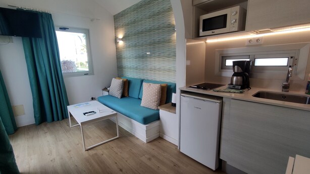 A compact living space with a sofa, a small table, a microwave, a coffee maker, and a mini fridge. - Canary Garden Club (San Bartolomé de Tirajana)