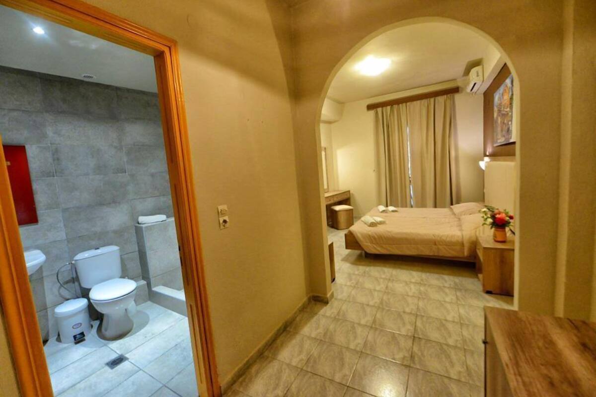 Un baño con inodoro, lavabo y ducha. El baño tiene suelo de baldosas y zona de ducha.
