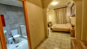 Een badkamer met toilet, wastafel en douche. De badkamer heeft een betegelde vloer en een douchegedeelte.