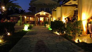 Un restaurante llamado "Blue Sea" con un sendero de piedra que lleva a la entrada, rodeado de follaje y palmeras.