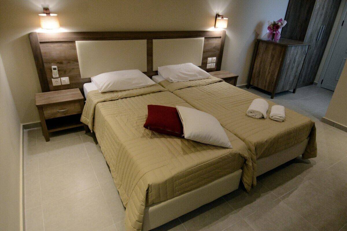 Una cama doble con cabecera de madera, dos mesitas de noche y un atril.