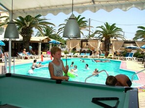 Ein Poolbereich mit Liegestühlen und Sonnenschirmen, umgeben von Palmen.