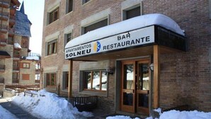A building with a sign reading "BAR RESTAURANTE SOLNEU" and a snow-covered entrance. - Apartamentos Solneu (Naut Aran)
