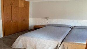 A bedroom with a bed, a wooden wardrobe, and a bedside table. - Apartamentos Solneu (Naut Aran)