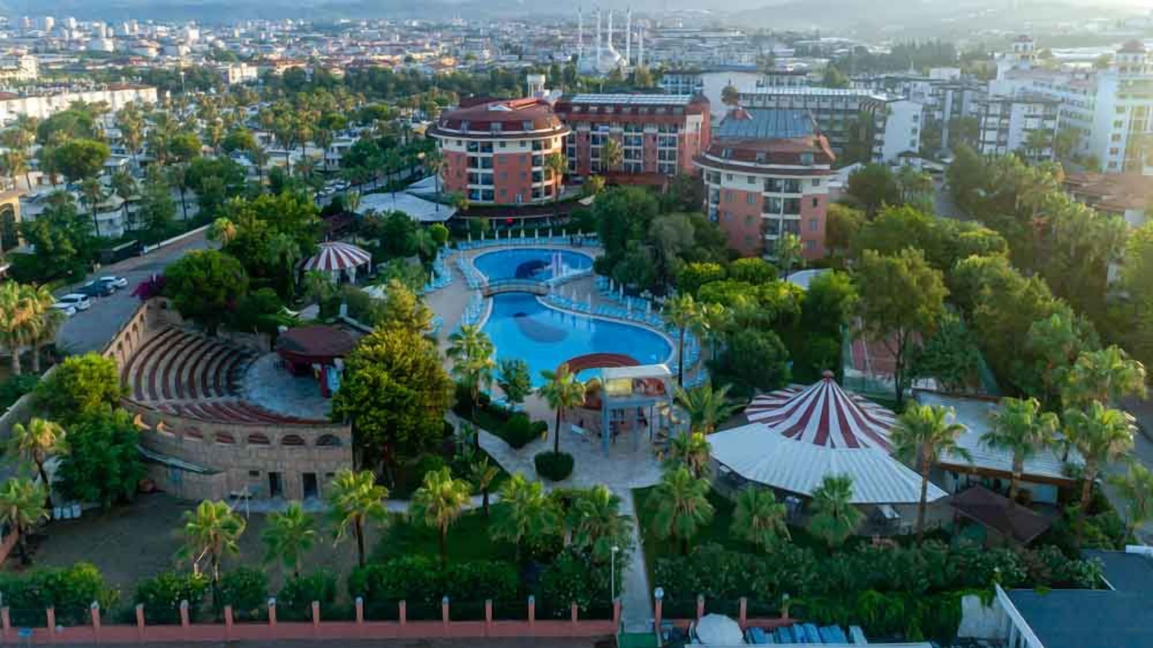Ein Resort mit einem zentralen Pool, mehreren Gebäuden und üppiger Bepflanzung.