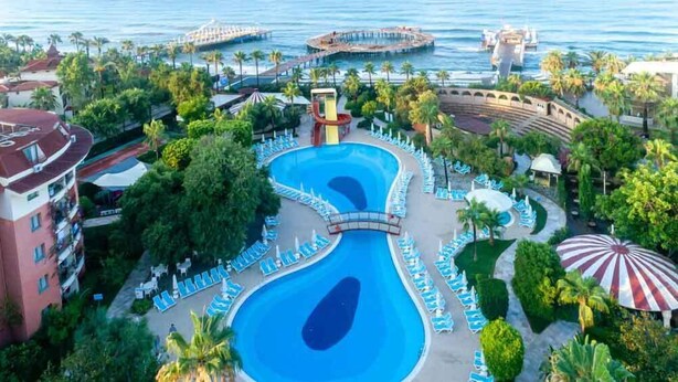 A resort with a large central pool, palm trees, and a waterfront view. - Palmeras Beach Hotel (Alanya)