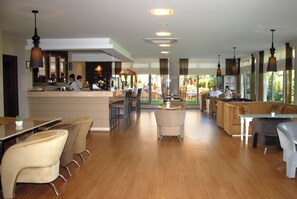 Un ristorante spazioso con zona bar, diverse opzioni di posti a sedere tra cui cabine e tavoli, e vista sull'esterno grazie a ampie finestre.