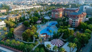 An aerial view of a resort with a central swimming pool, multiple buildings, and surrounding palm trees. - Palmeras Beach Hotel (Alanya)