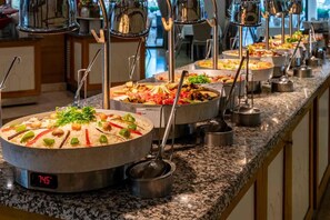 Un buffet con diversi piatti, tra cui riso e verdure, e una sveglia digitale che mostra l'ora.