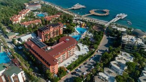 A resort with multiple buildings, a swimming pool, and a pier extending into the water. - Palmeras Beach Hotel (Alanya)
