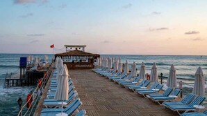 A beachside pier with lounge chairs and umbrellas, a bar named 'Palmeras', and the ocean in the background. - Palmeras Beach Hotel (Alanya)