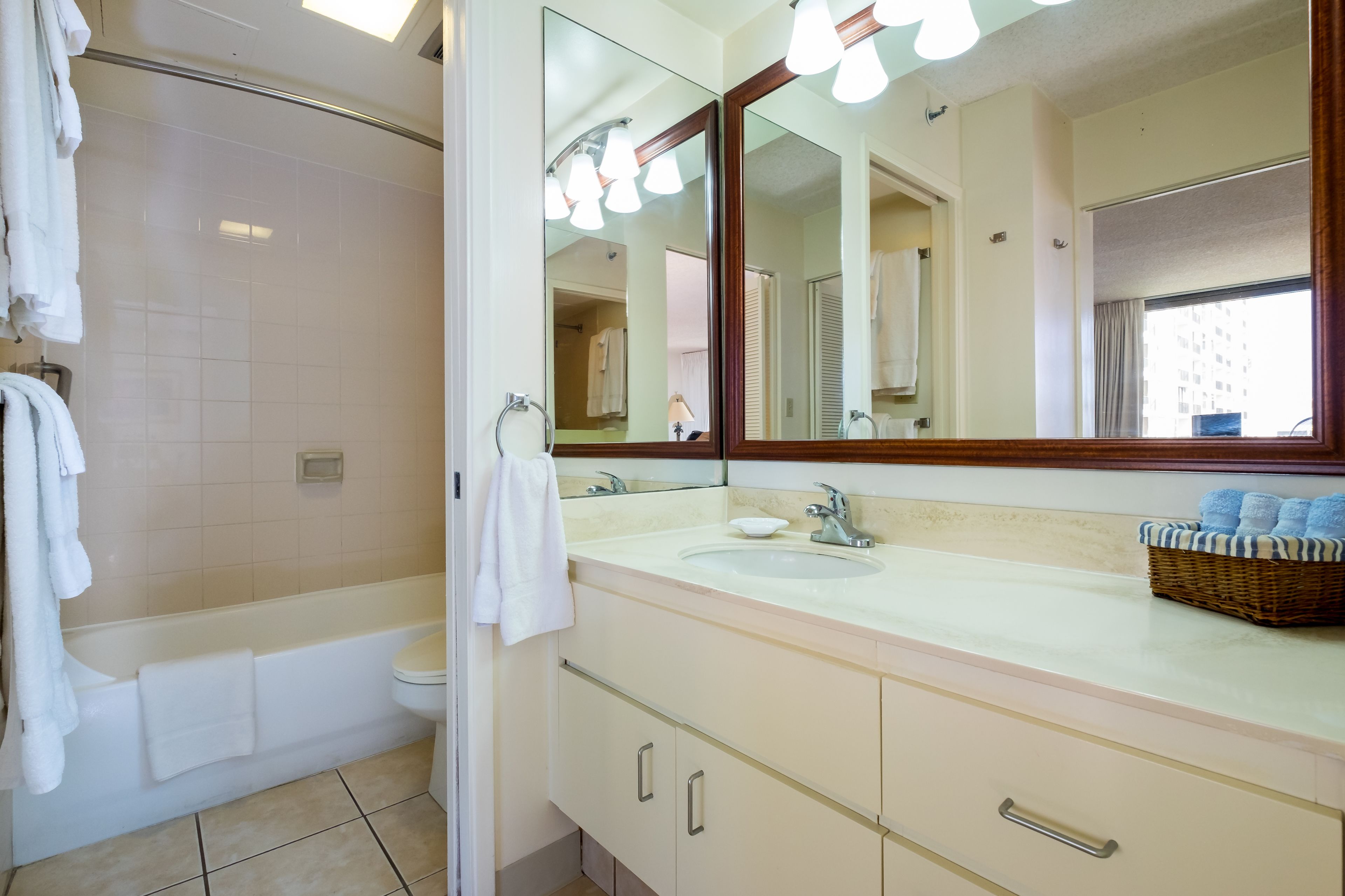 A bathroom with a bathtub, a sink, a mirror, and a window.