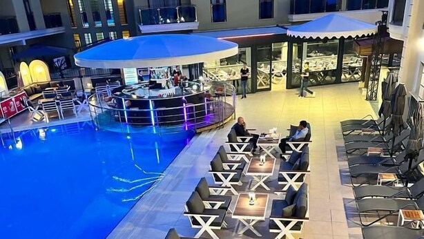 A poolside area with lounge chairs and tables, a pool, and a covered seating area. - Club Karakas Apart (Marmaris)