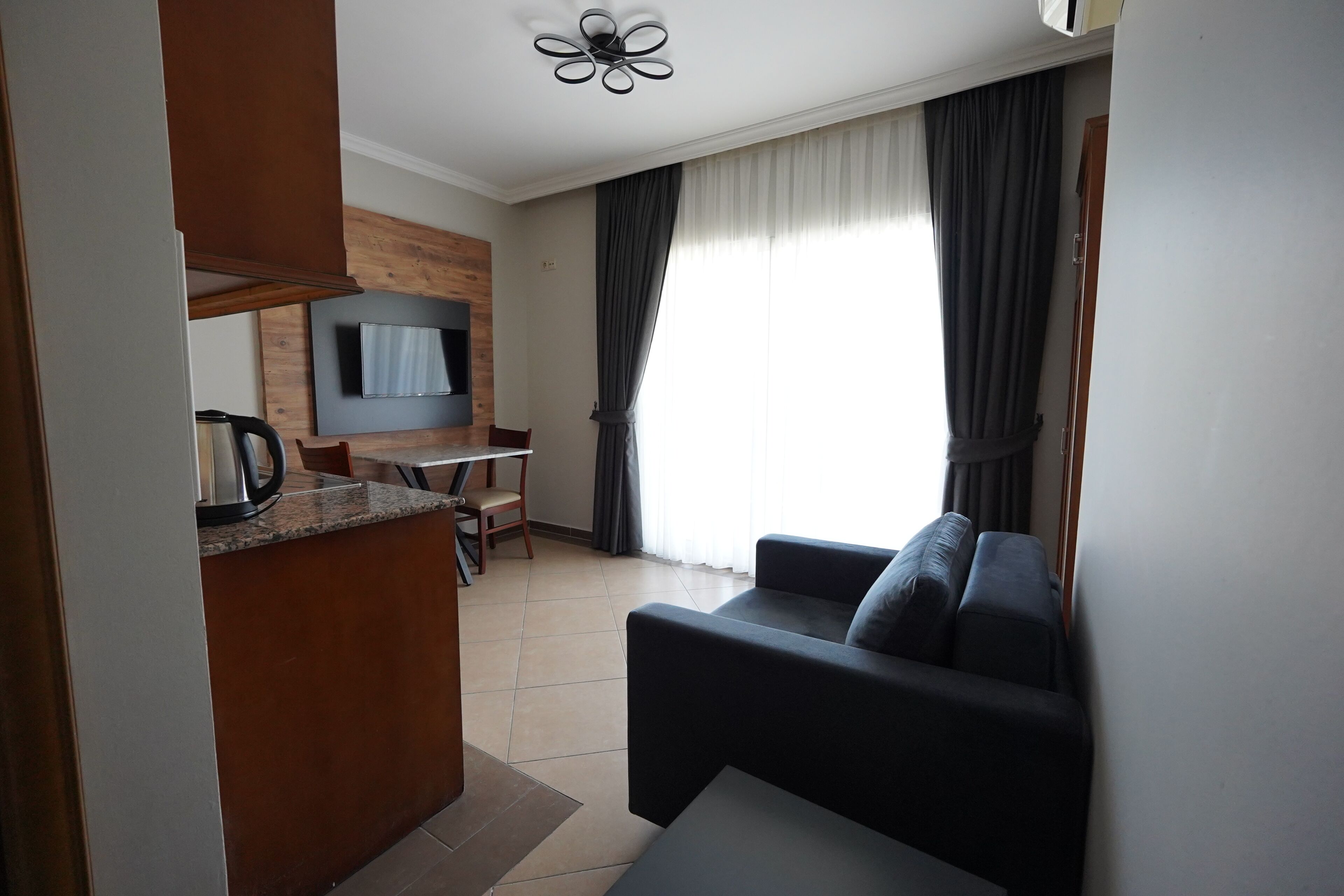 Uma sala de estar moderna com um sofá, uma televisão e um espaço de jantar com mesa e cadeiras.