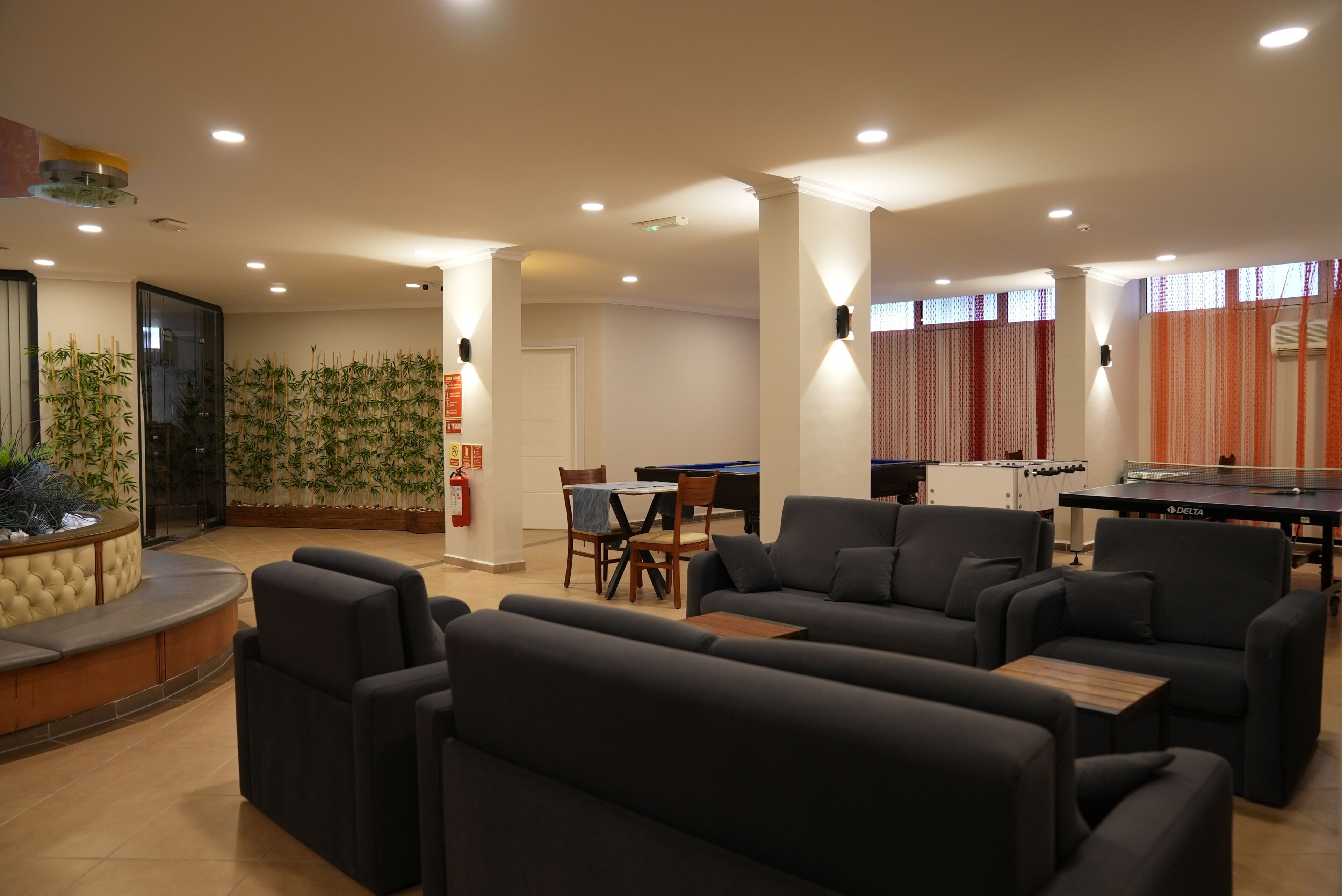 A modern lounge area with sofas, a pool table, and a ping pong table.