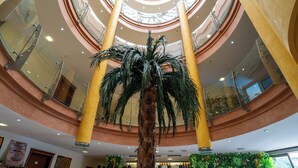 A multi-level atrium with a central palm tree, glass railings, and a green wall with plants. - Club Karakas Apart (Marmaris)