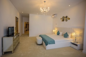 A bedroom with a bed, bedside table, lamp, TV, and a dresser. - Queen Vera Hotel (Constanta)