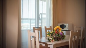 Un coin repas avec une table dressée pour deux personnes, un bouquet de fleurs et un four à micro-ondes posé sur la table.